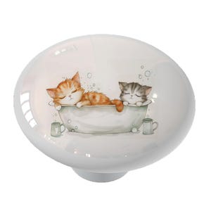 May include: Two adorable kittens, one orange and one gray, are taking a bath in a white bathtub with soap bubbles. The kittens are lying on their backs with their paws in the air. There are two green mugs on either side of the bathtub.