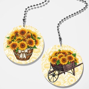 May include: Two round fan pull designs featuring sunflowers. One design shows a bouquet of sunflowers in a wooden barrel with a white ribbon. The other design shows a wheelbarrow full of sunflowers with red berries.