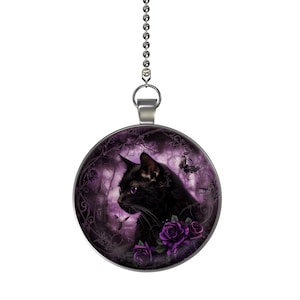 May include: A round, silver-toned pendant featuring a black cat with purple eyes, surrounded by purple roses and butterflies. The pendant hangs from a silver chain. The background is a dark purple, gothic-themed design.