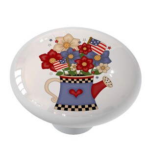 May include: A white ceramic knob with a blue and white watering can filled with red, white, and blue flowers. The flowers have red, white, and blue flags on them.