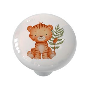 May include: White ceramic cabinet knob featuring a watercolor illustration of a cute tiger cub with orange and brown stripes. The knob has a glossy finish and a small, round base. Green leaves and a flower are also depicted.