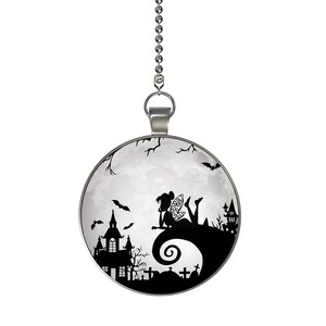 May include: A round, silver-toned pendant with a Halloween-themed design. The image features a silhouette of a fairy on a hill, a haunted house, bats, and a full moon. The pendant hangs from a silver chain.