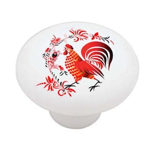 May include: A white ceramic knob with a red rooster illustration. The rooster is surrounded by red and black floral designs.