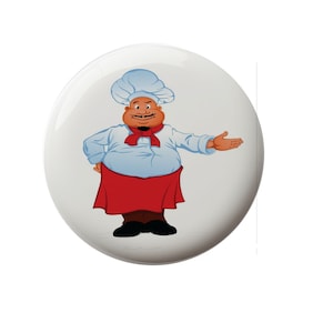 May include: A cartoon chef with a white chef's hat, a red bow tie, and a white shirt with a red apron is smiling and gesturing with his right hand.