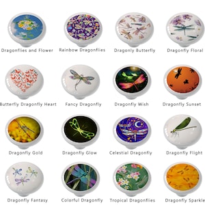 May include: A collection of decorative cabinet knobs with various dragonfly designs. Each knob features a different colorful dragonfly image, including floral, sunset, and fantasy themes. The knobs are white with a glossy finish.