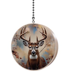 May include: A round wooden ceiling fan pull featuring a detailed illustration of a deer with large antlers. The deer is brown and white, set against a backdrop of muted colors, with red berries and branches.