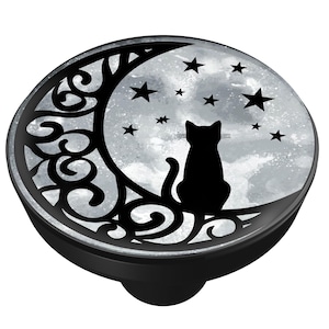 May include: A black and silver phone grip featuring a black cat silhouette sitting on a crescent moon with stars. The design is set against a watercolor-style background. The grip has a black base.