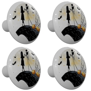 May include: Set of four ceramic cabinet knobs featuring a silhouette of Jack Skellington and Sally from the Nightmare Before Christmas movie. The knobs are white with a black and white image of the characters standing on a hill with a spiderweb and pumpkins in the background.