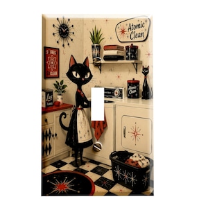 May include: A rectangular light switch plate featuring a black cat wearing a white apron in a laundry room. The scene includes a black and white checkered floor, a starburst clock, a sign reading Atomic Clean, and laundry appliances with starburst motifs.