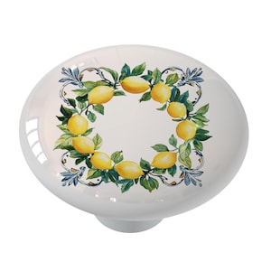 May include: White ceramic knob with a wreath of lemons and green leaves on a white background. The wreath is surrounded by a blue and white decorative border.