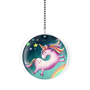 May include: A white ceiling fan pull with a colorful illustration of a unicorn with a rainbow tail and mane, flying through a starry night sky with a rainbow.