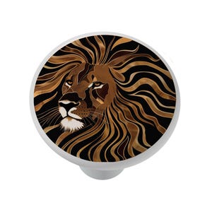 May include: A white cabinet knob featuring a detailed lion's head design. The lion's mane is depicted in shades of brown and gold against a black background. The knob is round and has a simple, white base.