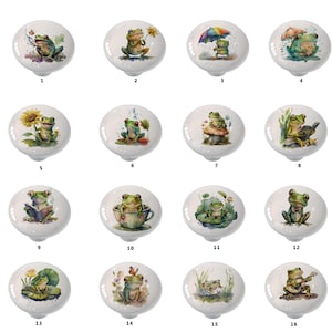 May include: Set of 16 ceramic knobs featuring various watercolor illustrations of frogs in different poses and settings. The frogs are depicted in shades of green, brown, and yellow, with details like flowers, mushrooms, and musical instruments.