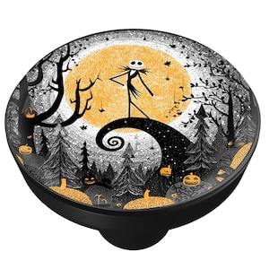 May include: A black cabinet knob featuring a Halloween-themed design. The image depicts a silhouetted figure standing on a swirling hill, with a full moon in the background. The design includes trees, pumpkins, and a spooky forest scene.