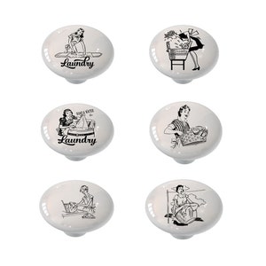 May include: Set of six white ceramic cabinet knobs with black and white illustrations of women doing laundry. The knobs feature vintage-style illustrations with text that says "Laundry" and "Soap & Water 5¢".