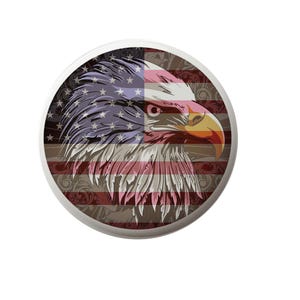 May include: A round sticker with a bald eagle head superimposed on an American flag. The eagle's head is facing right and has a yellow beak. The flag is red, white, and blue with a floral pattern in the background.