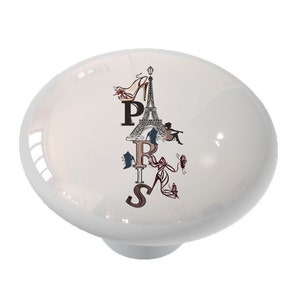 May include: White ceramic knob with a graphic of the Eiffel Tower, high heels, and the word "PARIS" in a stylized font.