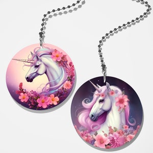 May include: Two round fan pull charms featuring white unicorns with pink manes and floral wreaths. The unicorns are set against a pink and purple background with pink flowers.