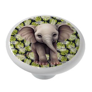 May include: A ceramic knob with a cute cartoon illustration of a baby elephant standing in a jungle setting with green leaves.