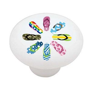 May include: A white ceramic knob with a design of eight colorful flip flops arranged in a circle.