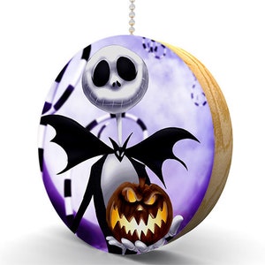 May include: A round wooden pull chain with a purple background and a black and white image of Jack Skellington from The Nightmare Before Christmas holding a jack-o-lantern.