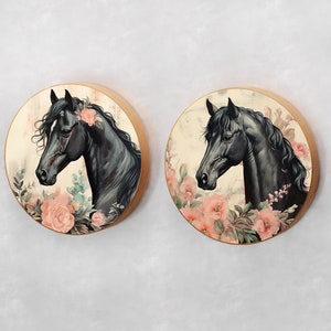 May include: Two round wooden wall decor pieces with black horses and pink flowers. The horses are facing to the right and have black manes and tails. The flowers are pink and white and are arranged around the horses.