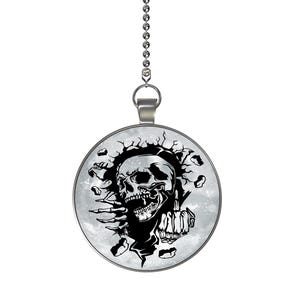 May include: A silver chain with a round pendant featuring a black and white illustration of a skull breaking through a cracked surface. The skull has a menacing expression and is surrounded by a gray background.