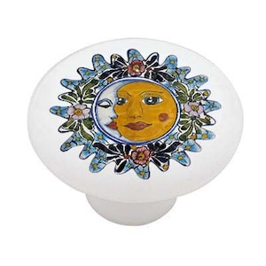 May include: Ceramic knob with a colorful sun and moon design. The sun is yellow with a human face and the moon is white with a crescent shape. The design is surrounded by blue, green, and pink flowers.