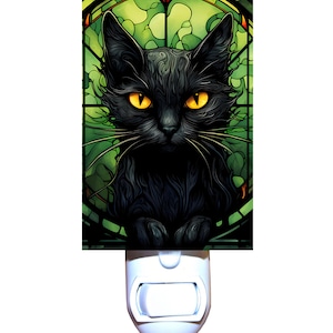 May include: A black cat with yellow eyes is featured in a stained glass style design on a white nightlight. The nightlight plugs into an outlet.