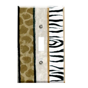 May include: A light switch cover with a zebra and giraffe print. The cover is white with black and brown stripes. The zebra print is on the right side of the cover and the giraffe print is on the left side.