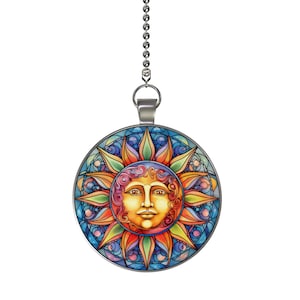 May include: A round, stained-glass style suncatcher with a smiling sun face. The sun has a yellow face, surrounded by orange, red, and yellow rays. The background is blue with a silver chain for hanging.