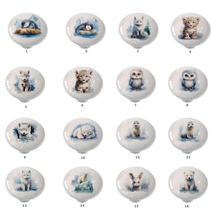 May include: Set of 16 ceramic cabinet knobs featuring watercolor illustrations of various arctic animals, including penguins, owls, foxes, polar bears, and seals. The knobs are white with a glossy finish.