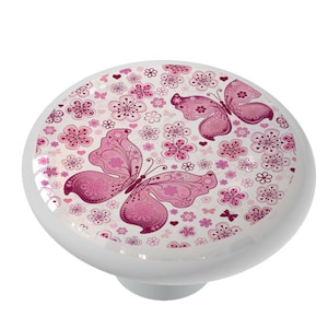 May include: A white ceramic knob with a pink and white butterfly and floral design.