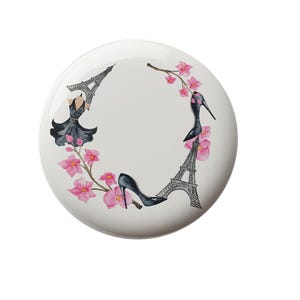 May include: A white ceramic plate with a black and white illustration of the Eiffel Tower, a black dress, and pink flowers. The illustration is surrounded by a circle of pink flowers.