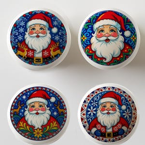 May include: Four white cabinet knobs with colorful Santa Claus designs. Each knob features a different Santa illustration with a red hat, white beard, and a blue decorative border with snowflakes, reindeer, and floral patterns.