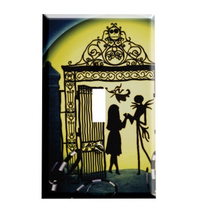May include: A light switch cover featuring a silhouette of Jack Skellington and Sally from the Nightmare Before Christmas movie. The image is set against a yellow moon with a black iron gate in the background.