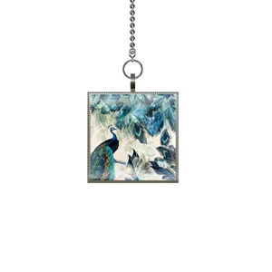 May include: A silver chain with a square pendant featuring a peacock with blue and green feathers on a white background.