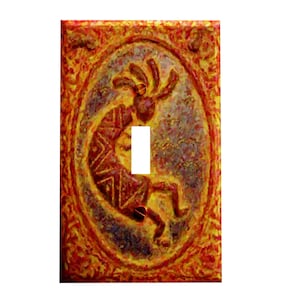 May include: A light switch cover with a red, orange, and yellow design featuring a stylized Native American dancer in an oval frame.