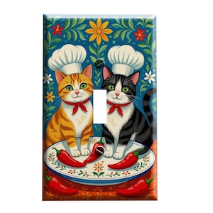 May include: Decorative light switch cover featuring two cartoon cats wearing chef hats and red bow ties. An orange tabby and a black and white cat sit on either side of the switch. A plate of red chili peppers is in front of them, with a blue floral background.