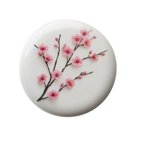 May include: A white plate with a delicate branch of pink cherry blossoms. The blossoms are arranged in a natural, flowing pattern.