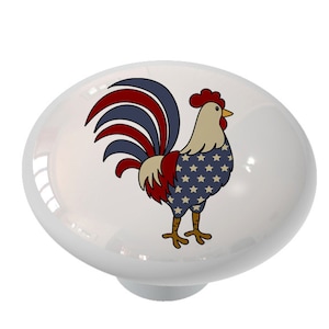 May include: A ceramic knob with a rooster design. The rooster is wearing a blue, red, and white pattern reminiscent of the American flag.