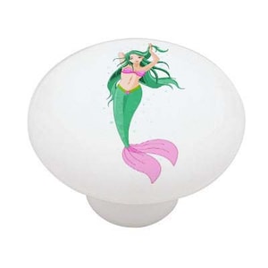 May include: A ceramic knob with a white background and a cartoon image of a mermaid with green hair and a pink tail.