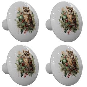May include: Four white ceramic cabinet knobs with a decorative owl design. Each knob features a detailed illustration of a brown and white owl perched on a branch with a green ornament and red berries.