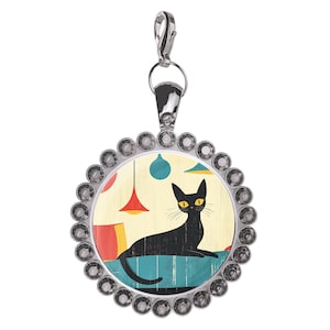 May include: A silver-toned charm pendant with a black cat illustration. The cat is lying down on a blue surface, with a yellow background and red and blue hanging lamps. The charm is surrounded by a ring of clear crystals.