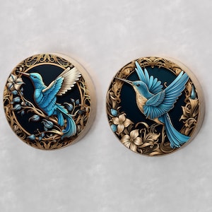 May include: Two round decorative wall plaques with ornate gold frames and blue hummingbirds with intricate details on a black background.