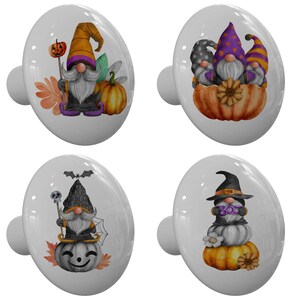 May include: Four white ceramic cabinet knobs with Halloween gnome designs. Each knob features a different gnome illustration with pumpkins, bats, and the word "BOO". The knobs have a glossy finish and are perfect for adding a festive touch to furniture.