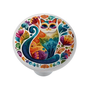 May include: A white cabinet knob featuring a colorful cat design. The cat is surrounded by a vibrant floral pattern in shades of blue, orange, purple, and green. The knob has a smooth, rounded shape.