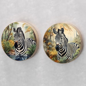 May include: Two round wall decor pieces featuring a black and white zebra standing in a lush green jungle setting. The zebra is depicted in a realistic style with detailed markings and a natural pose.