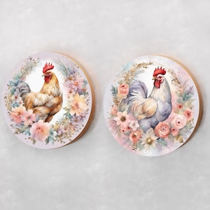 May include: Two round wooden wall plaques with a watercolor design of roosters surrounded by flowers. The roosters are in different poses and have different colored feathers. The flowers are in shades of pink, white, and yellow.