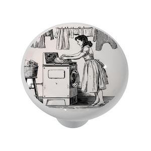 May include: Black and white illustration of a woman doing laundry in a vintage washing machine. The woman is wearing a dress and is standing next to the machine, which has a basket of clothes on top. There are clothes hanging on a line in the background.